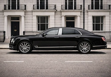 Chauffeur standing beside a pristine Bentley luxury saloon outside a premier London hotel in Mayfair